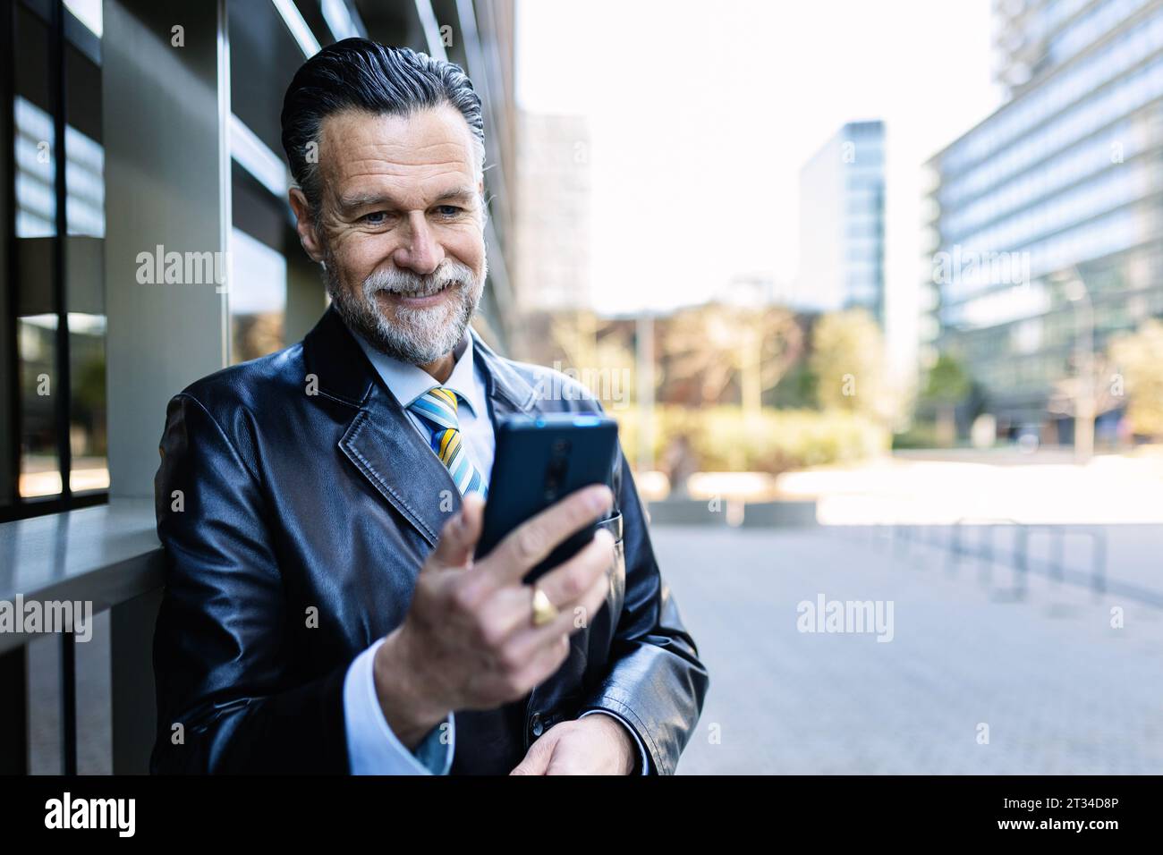 Reifer Geschäftsmann mit Smartphone in der Stadtstraße. Stockfoto