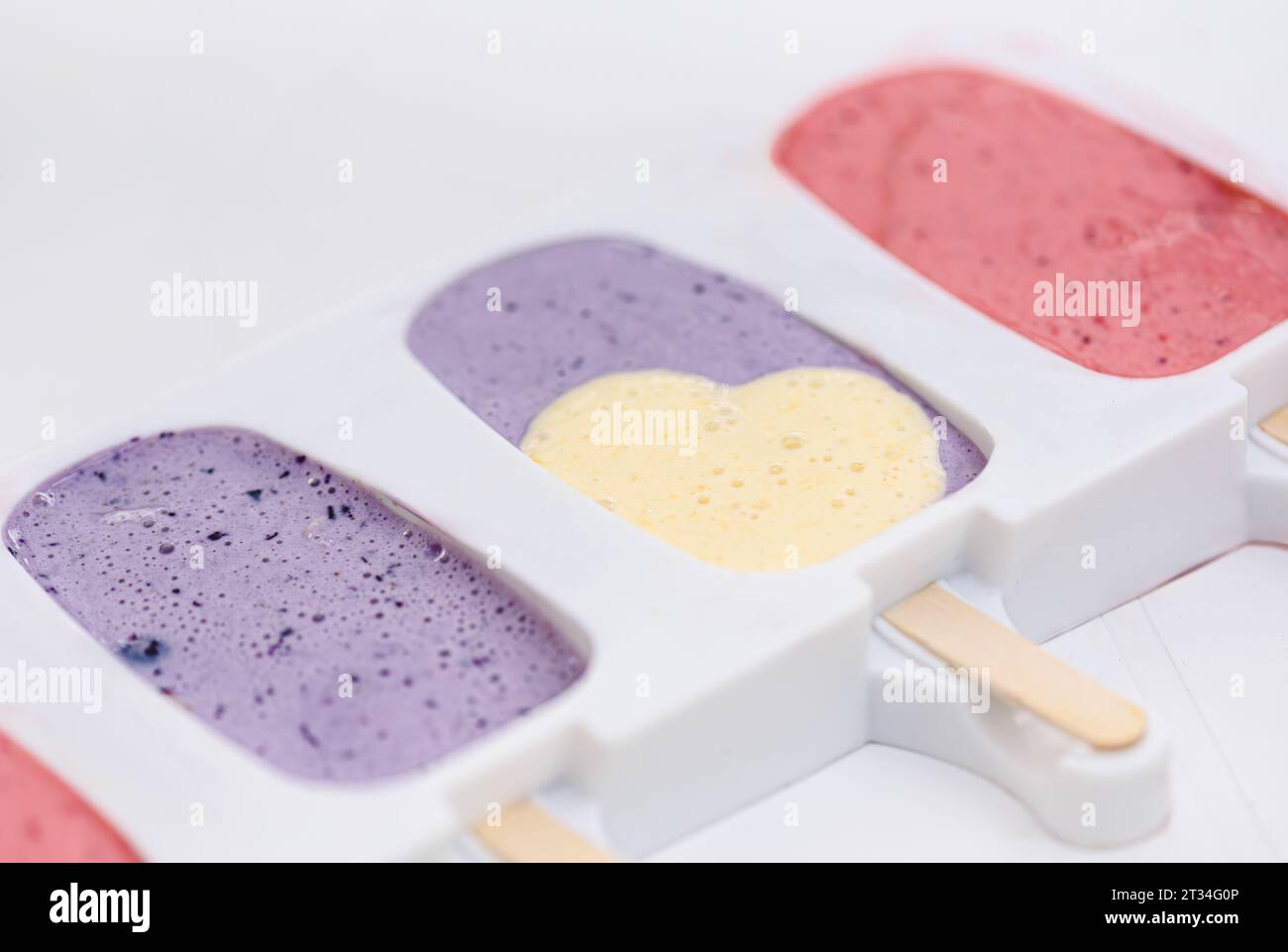 Hausgemachtes, farbenfrohes Fruchteis mit Herzform in Silikoneisform Stockfoto