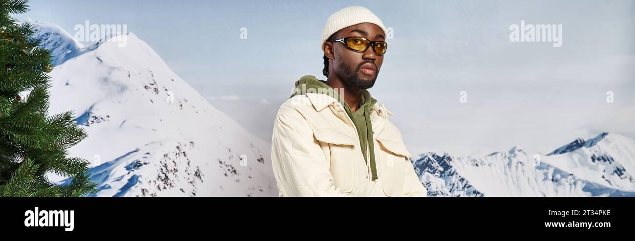 Stilvoller, gut aussehender Mann in Winterjacke und Mütze mit Sonnenbrille, Blick auf Kamera, Banner Stockfoto