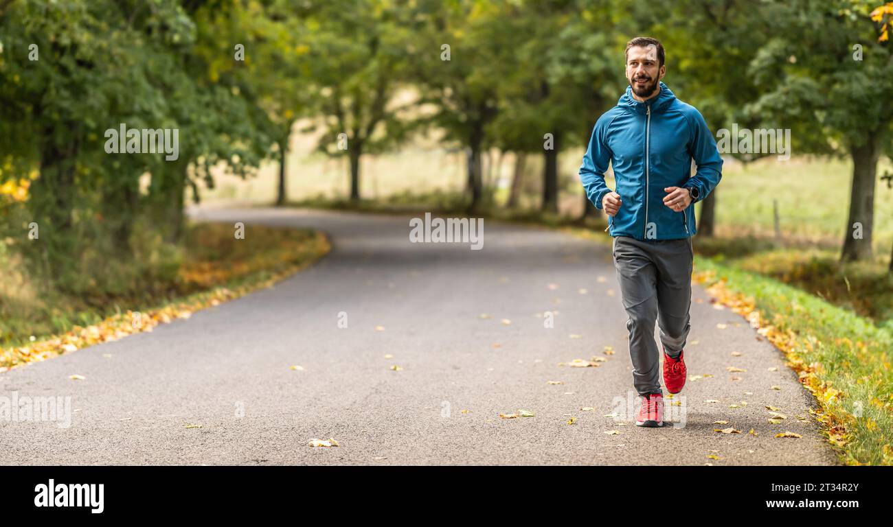 Ein junger Mann trainiert und läuft in einem Herbstpark. Stockfoto