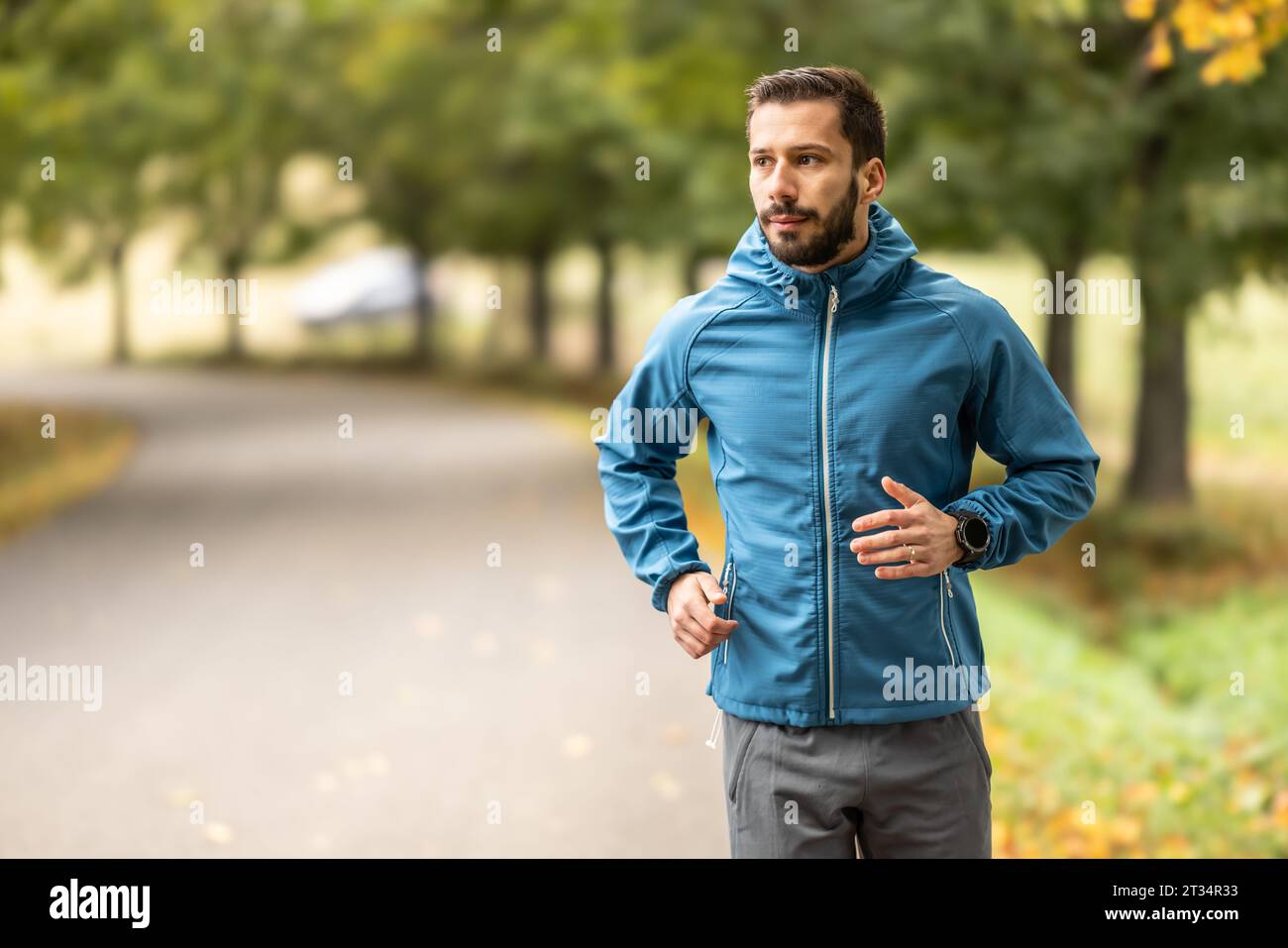 Ein junger Mann trainiert und läuft in einem Herbstpark. Stockfoto