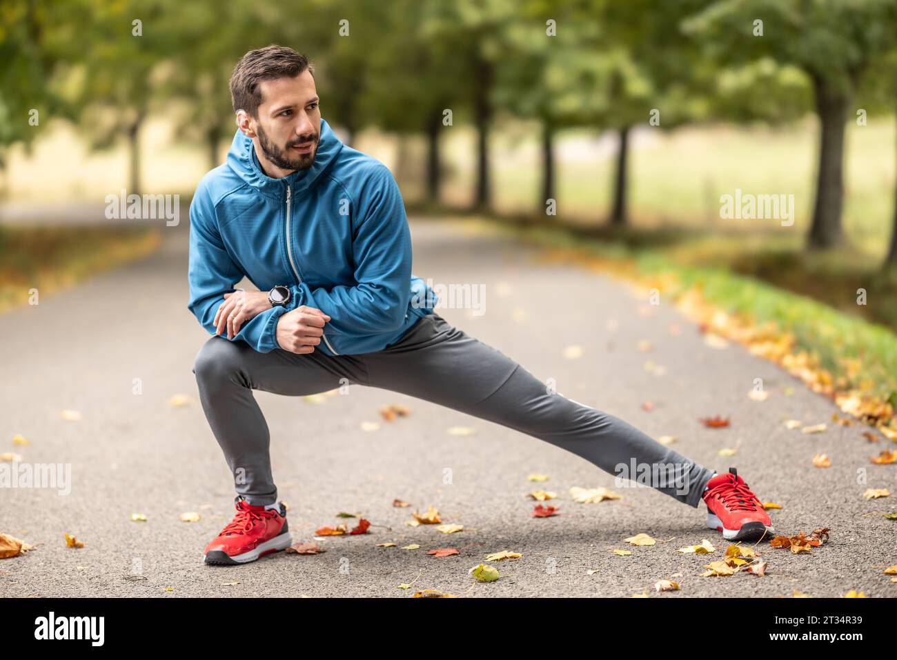 Ein junger Athlet wärmt sich vor dem Lauftraining im Park auf. Sie erwärmt den unteren Teil des Körpers. Stockfoto
