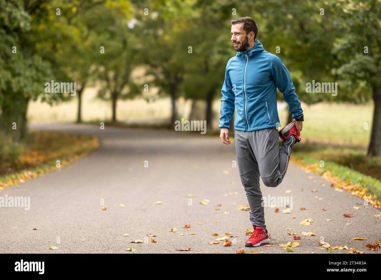 Ein junger Athlet wärmt sich vor dem Lauftraining im Park auf. Sie erwärmt den unteren Teil des Körpers. Stockfoto