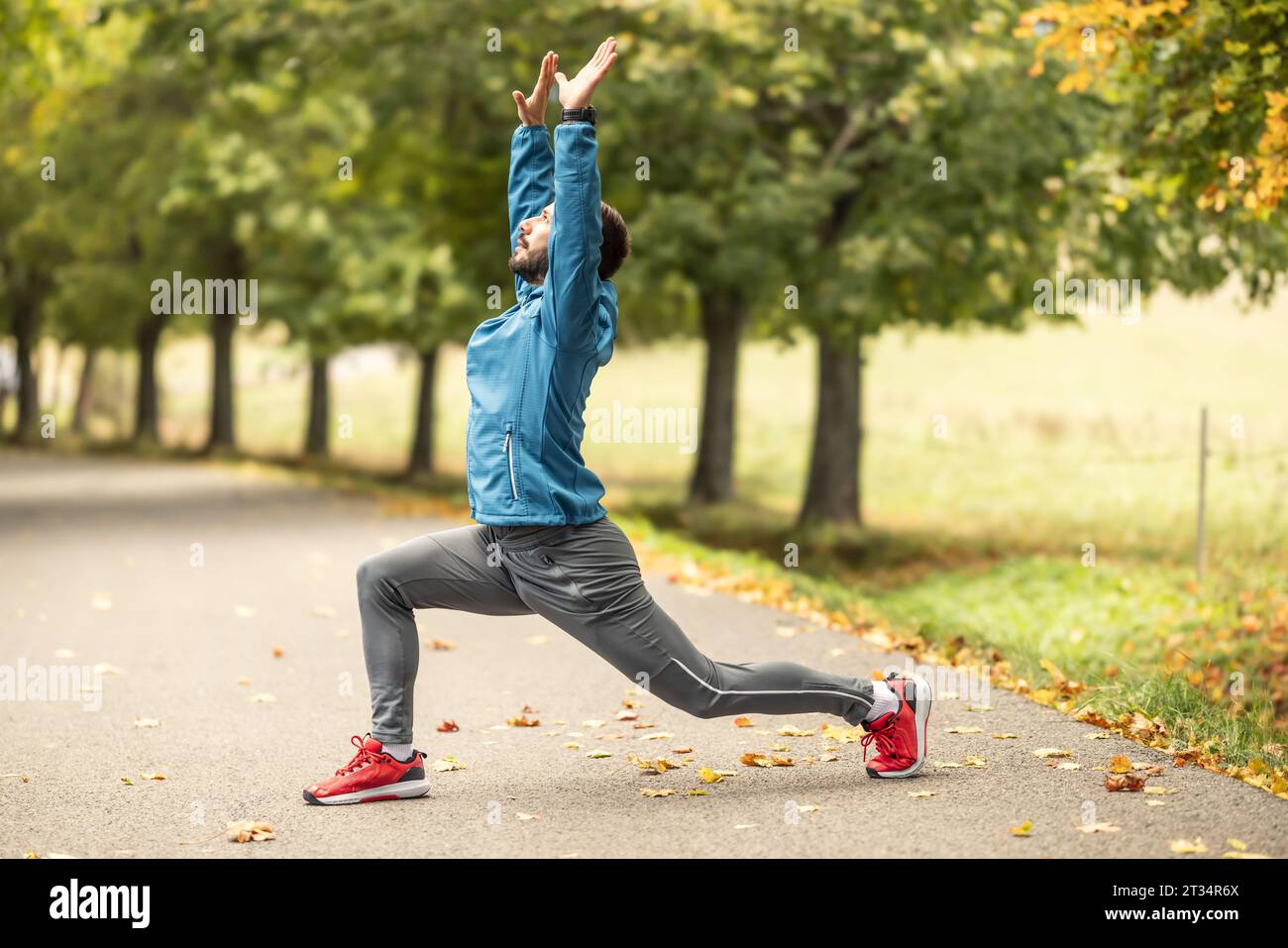 Ein junger Athlet wärmt sich vor dem Lauftraining im Park auf. Sie erwärmt den oberen und unteren Teil des Körpers. Stockfoto
