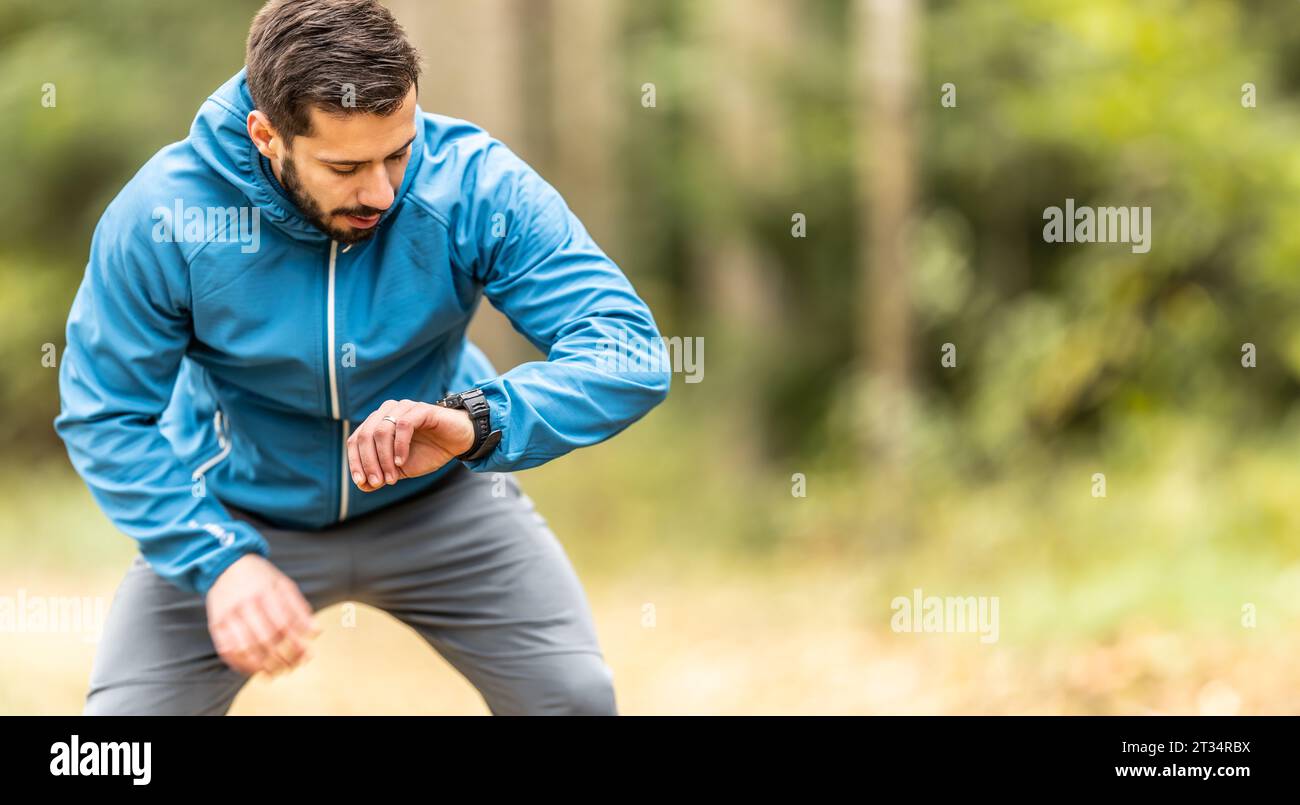 Ein junger Athlet überprüft seine Herzfrequenz auf einer intelligenten Uhr. Stockfoto