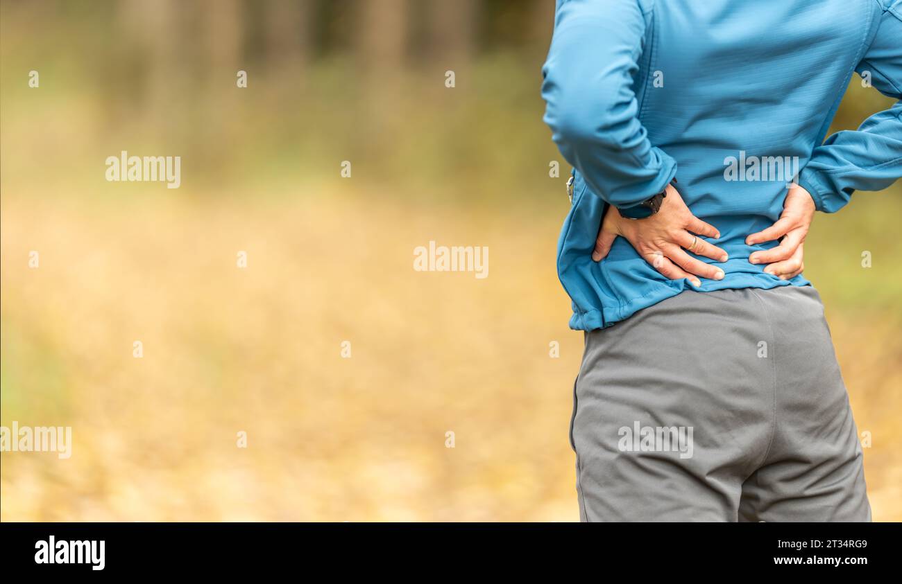 Junger Mann mit einer Sportfigur und einer unteren Rückenverletzung. Rückenschmerzen beim Sport. Stockfoto