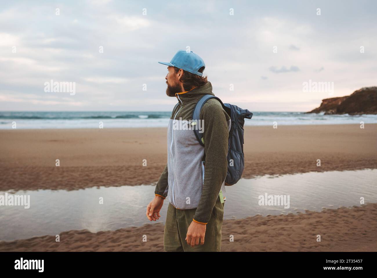 Mann, der alleine am Strand mit Rucksack gesunder Lebensstil aktiv Sommerurlaub Reisende im Freien genießt Meerblick Stockfoto
