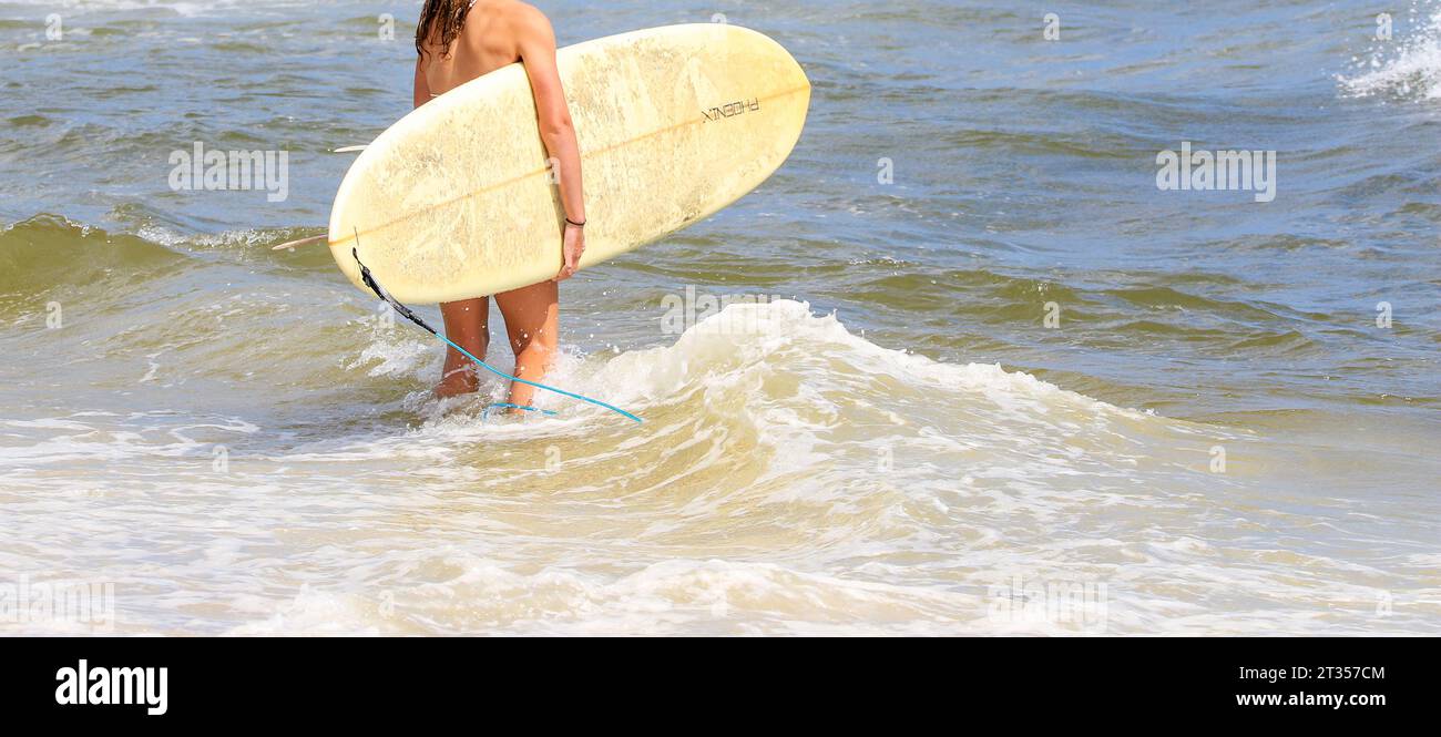 Ein Surfer, der am Rand des Wassers steht und bereit ist, ins Meer zu gehen, um am Strand zu surfen. Stockfoto