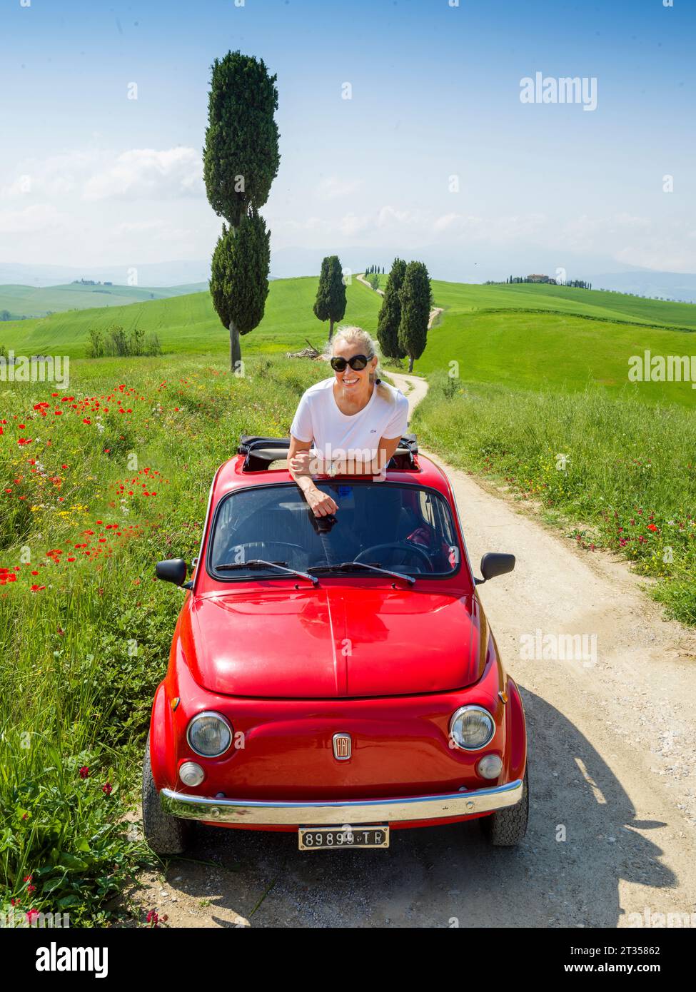 Frau genießt eine Vintage Fiat 500 Fahrt in der wunderschönen Landschaft der Toskana, Val D'Orcia Stockfoto