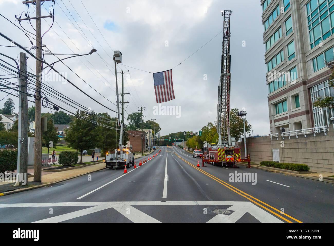 Amerikanische Flagge hängt am Feuerwehrauto über der gesperrten Straße zur Vorbereitung des 5-km-Rennens, Conshohocken, PA USA Stockfoto