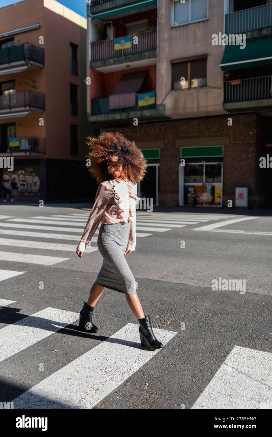 Junge Frau mit Afro Frisur Überqueren der Straße in der Stadt Stockfoto