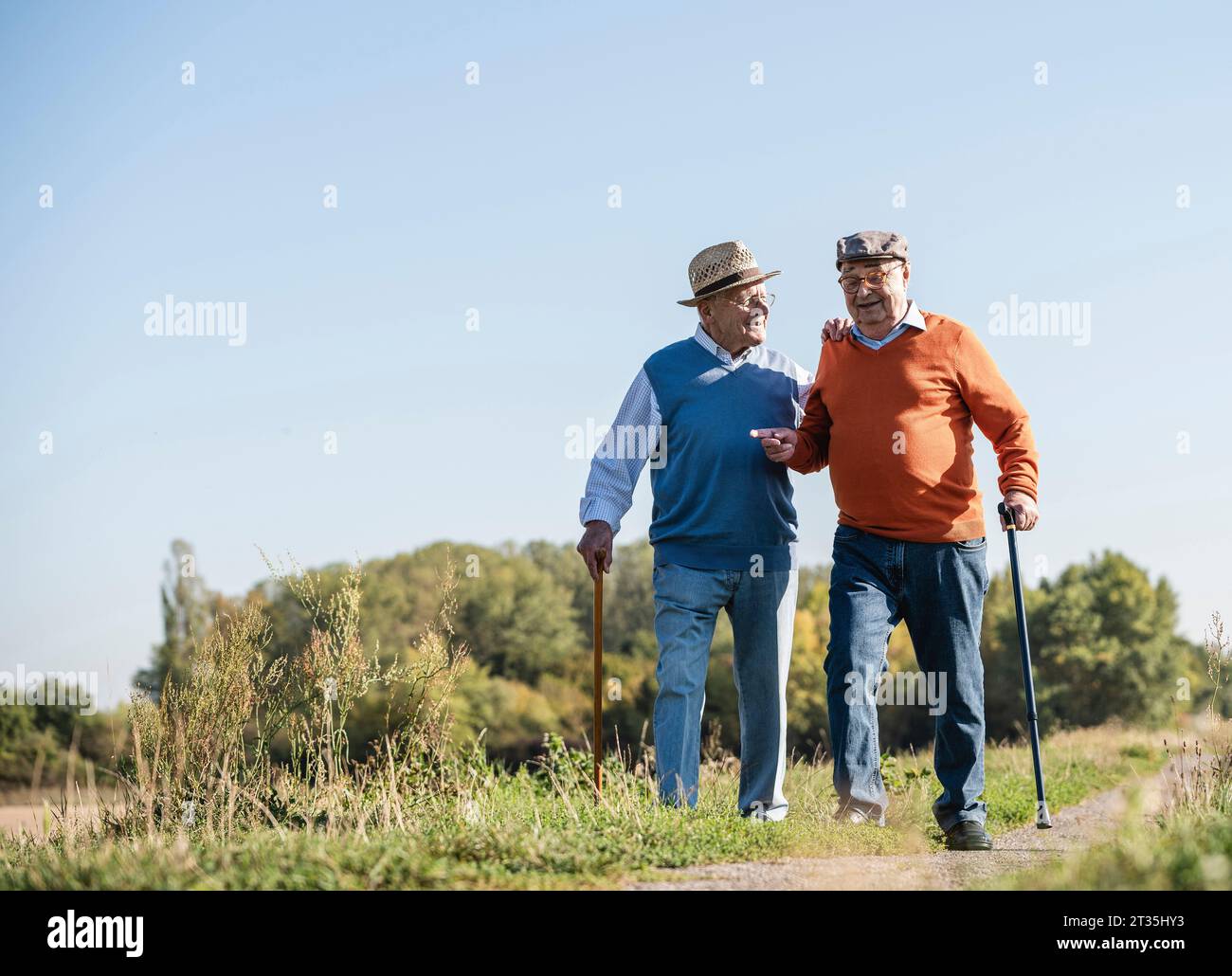 Zwei alte Freunde, die einem durch die Felder spazieren, reden über alte Zeiten Stockfoto