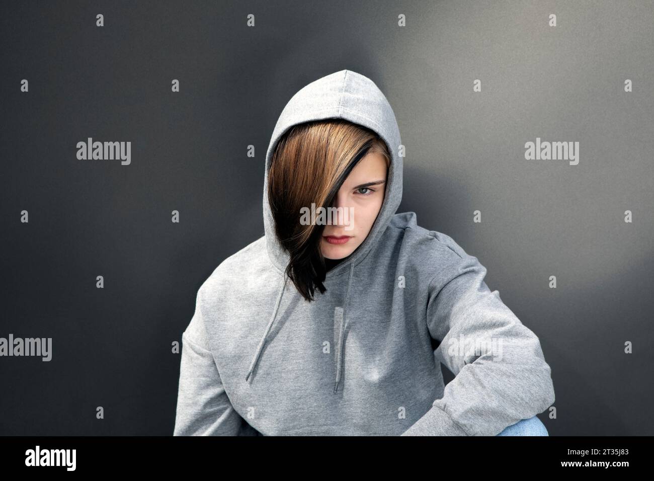 Teenager-Mädchen mit Kapuzenhemd vor grauem Hintergrund Stockfoto