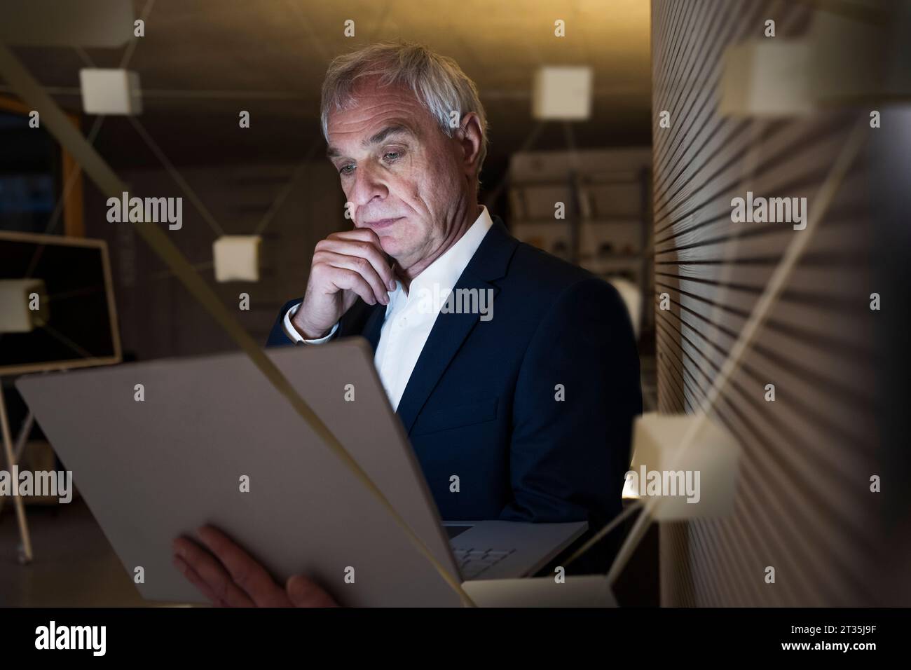 Digitales Composite-Bild eines durchdachten Geschäftsmannes mit Laptop im Büro Stockfoto