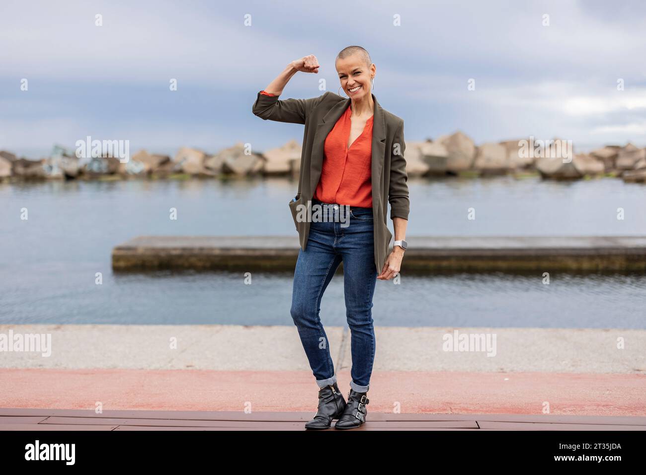 Lächelnde, rasierte Kopffrau, die Muskeln auf dem Pier beugt Stockfoto