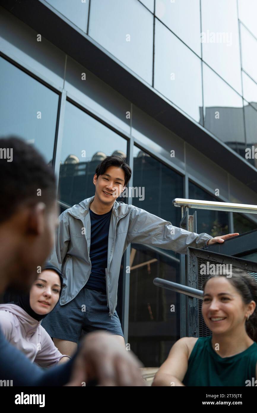 Lächelnder Mann, der mit Freunden vor dem Gebäude spricht Stockfoto