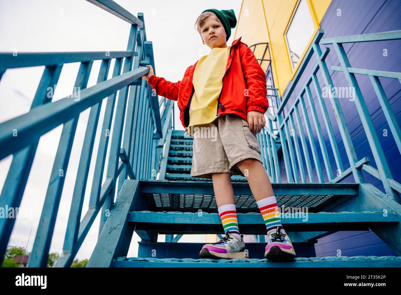 Junge in roter Jacke, der auf einer Metalltreppe steht Stockfoto