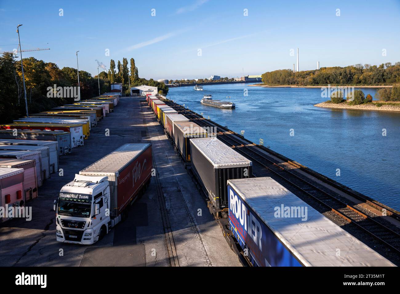 Lkw-Anhänger stehen am Westkai-Terminal des Rheinhafens Niehl, Frachtschiff fährt in den Hafen ein, Köln, Deutschland. LKW-Anhaenger stehen am Westk Stockfoto