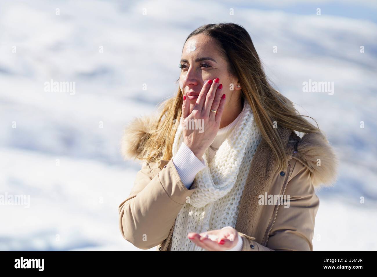 Frau, die im Winter Sonnencreme aufträgt Stockfoto