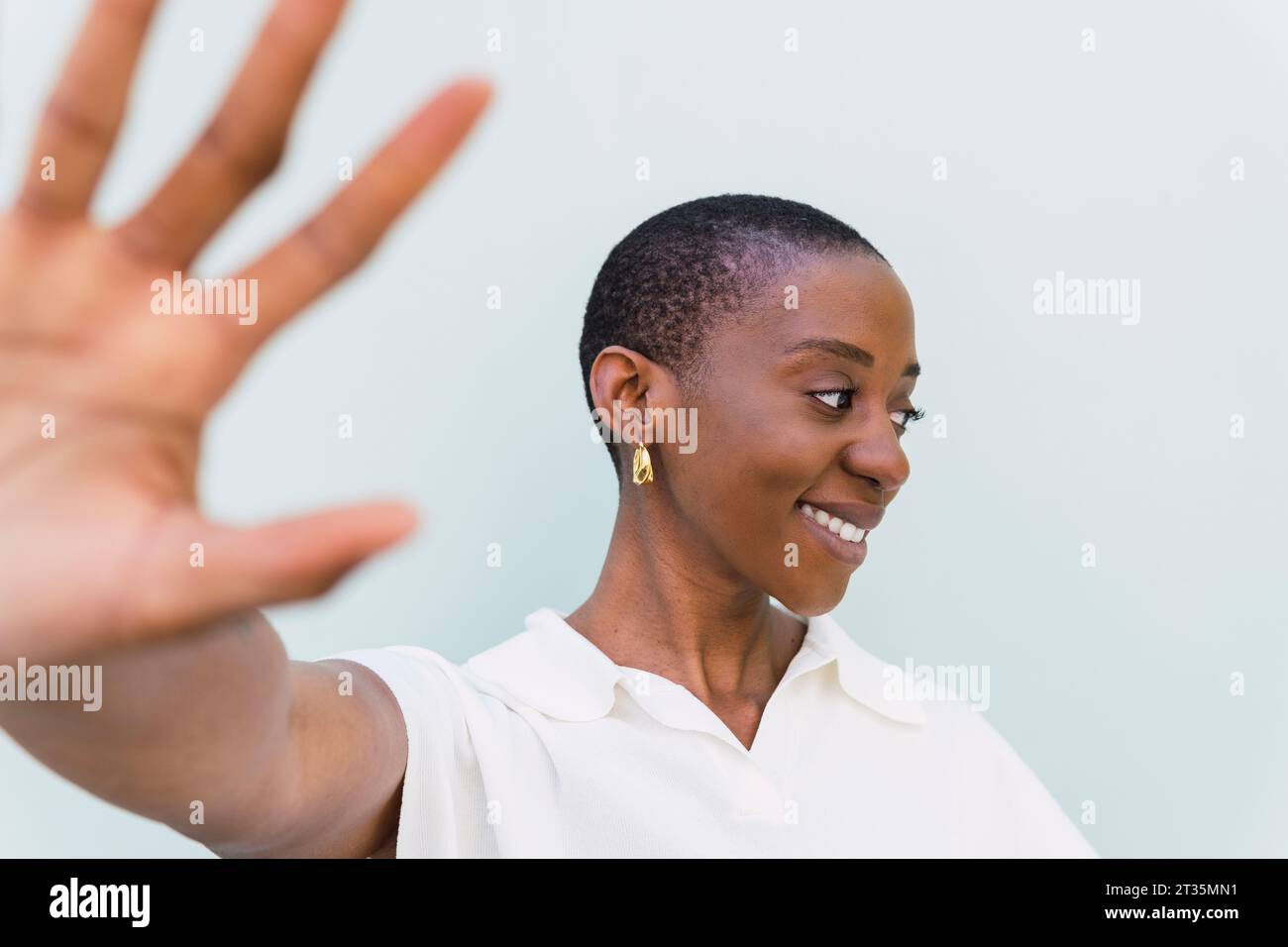 Glückliche junge Frau mit Stop-Geste vor weißem Hintergrund Stockfoto