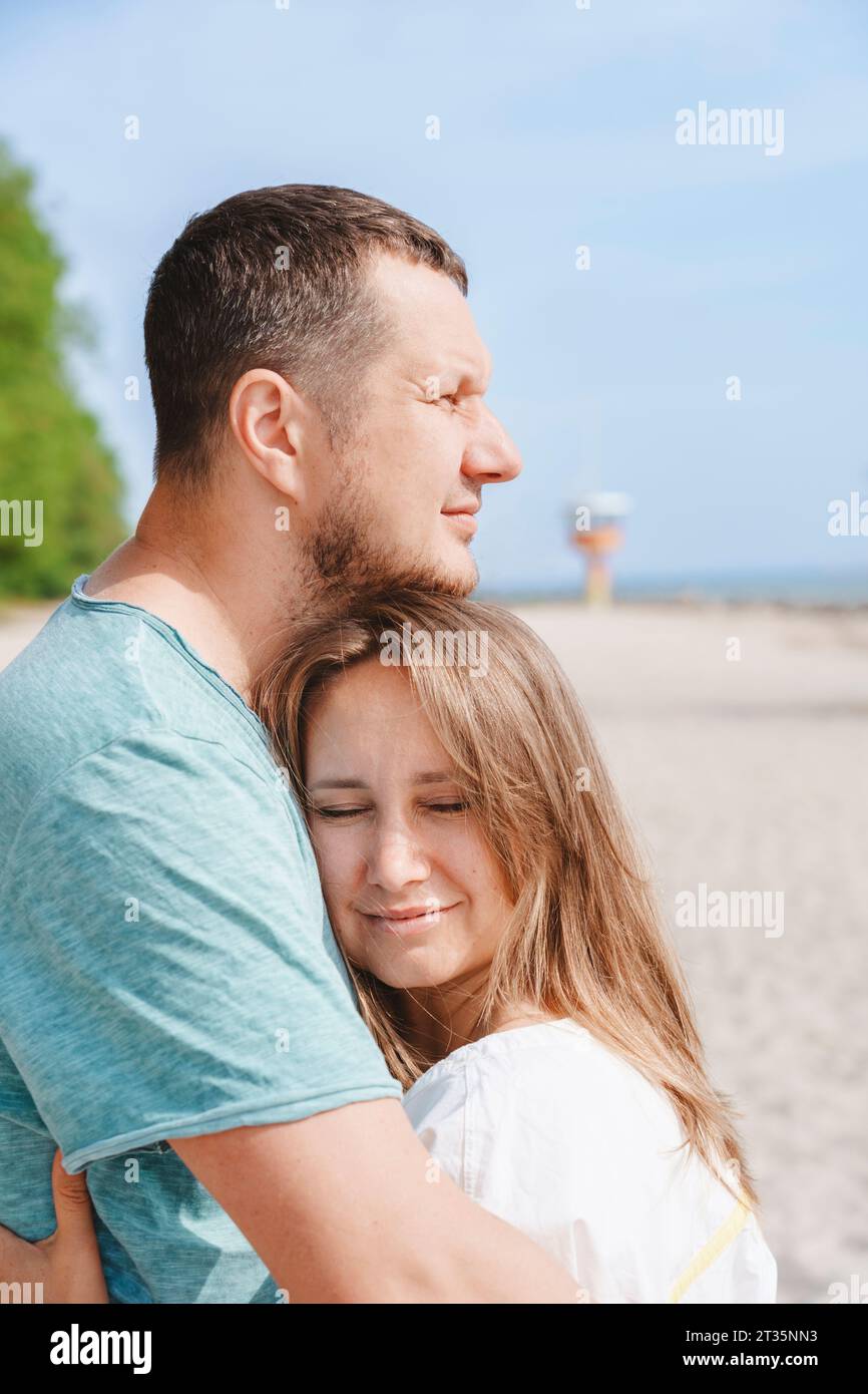 Glückliche Paare, die sich am Strand umarmen Stockfoto