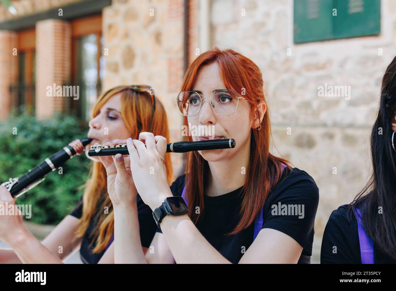 Frau mit Brille, die Flöte mit Gruppe spielt Stockfoto