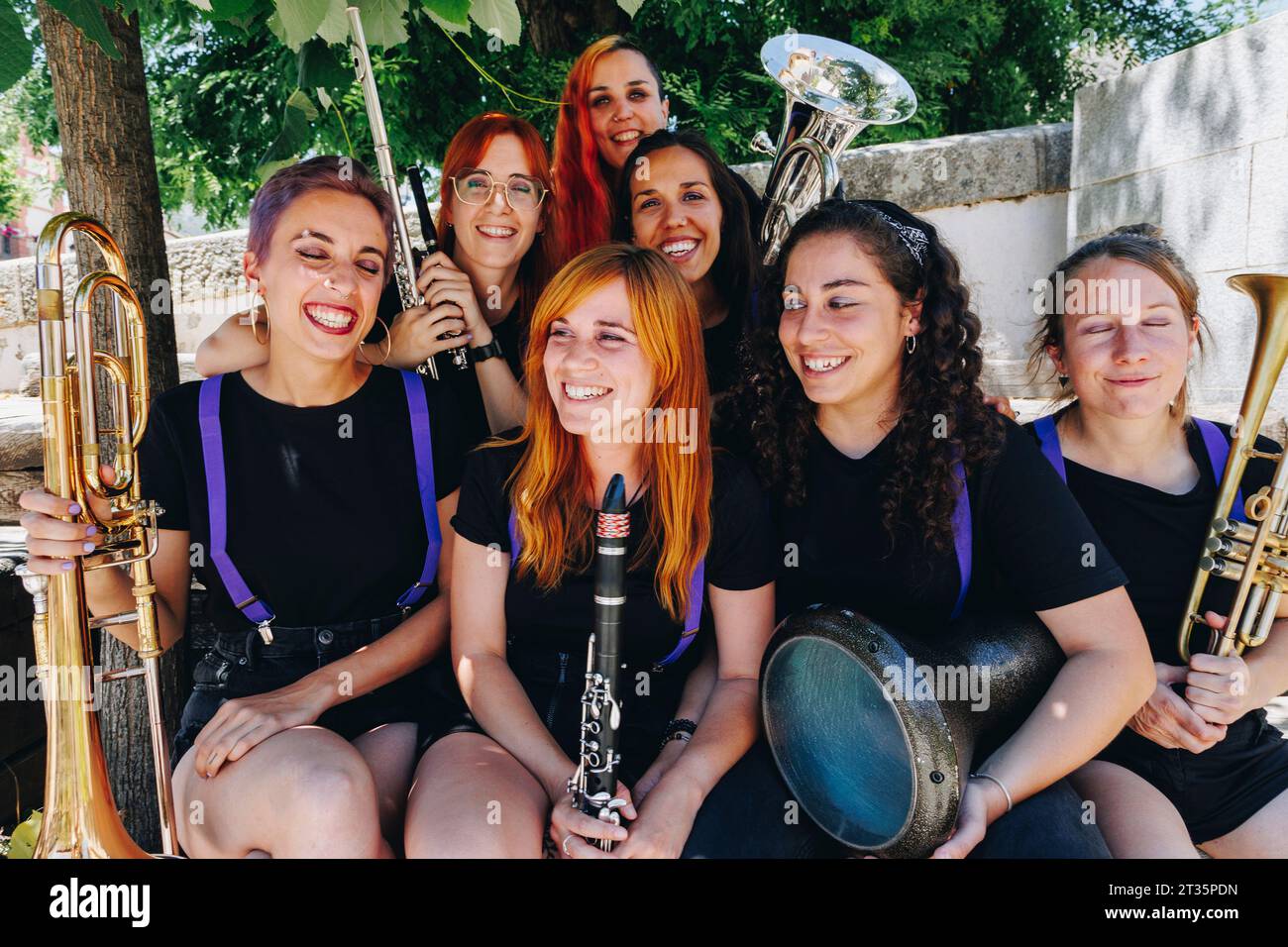 Fröhliche Frauen-Volksmusikgruppe, die zusammen mit Blasinstrumenten sitzt Stockfoto