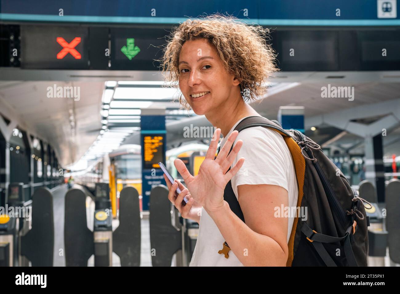 Geschäftsfrau winkt am Bahnhof Stockfoto