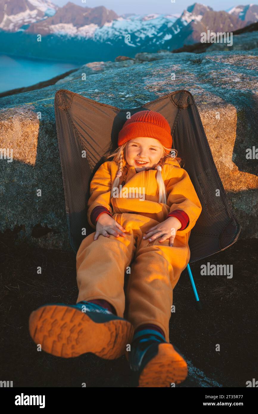 Kind sitzend im Campingstuhl Outdoor Reise in den Bergen Kind Wandern Abenteuer Urlaub Camping Familie gesunde Lebensweise Stockfoto