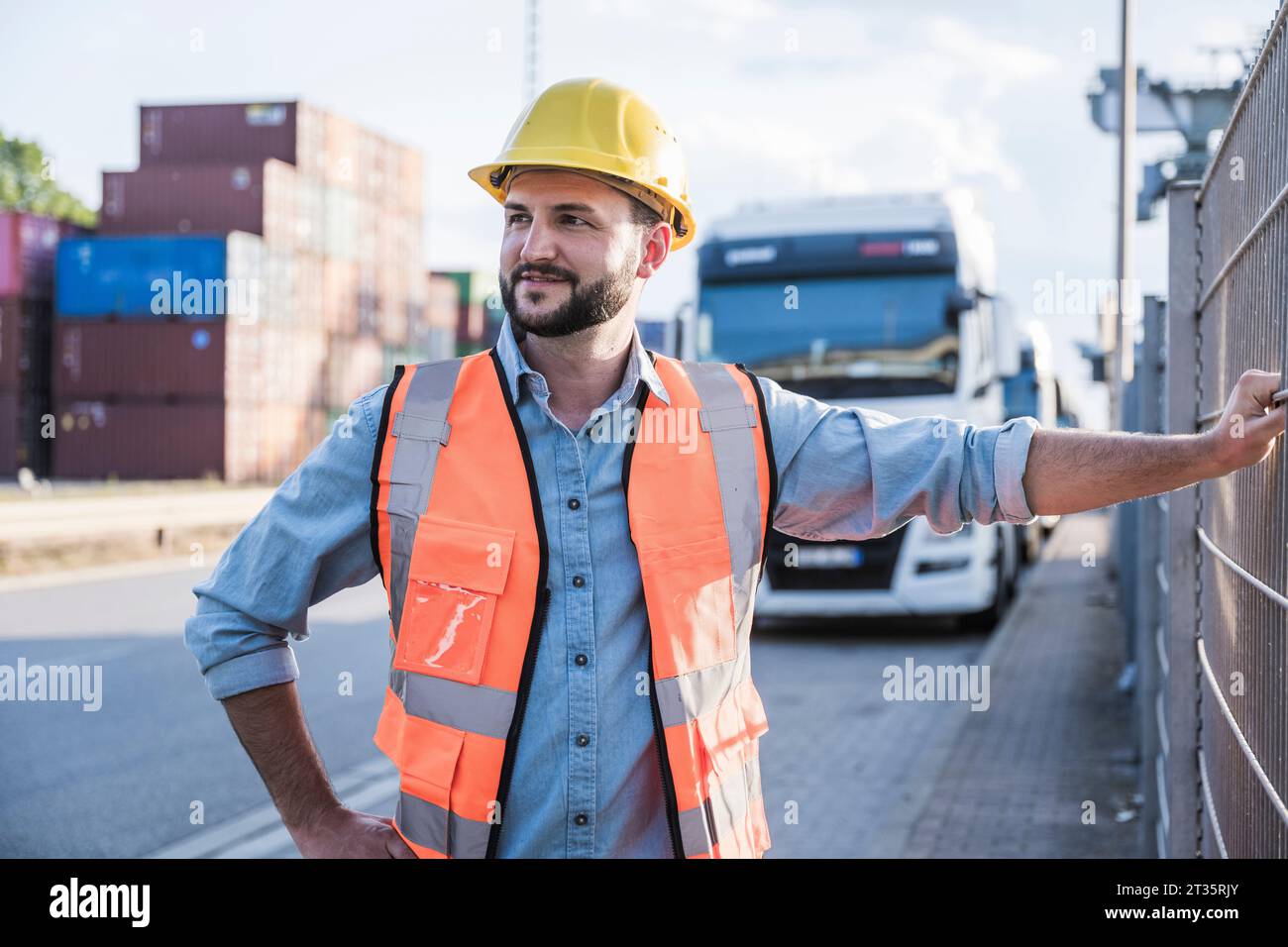 Lächelnder Logistiker mit Schutzhelm vor dem Lkw Stockfoto