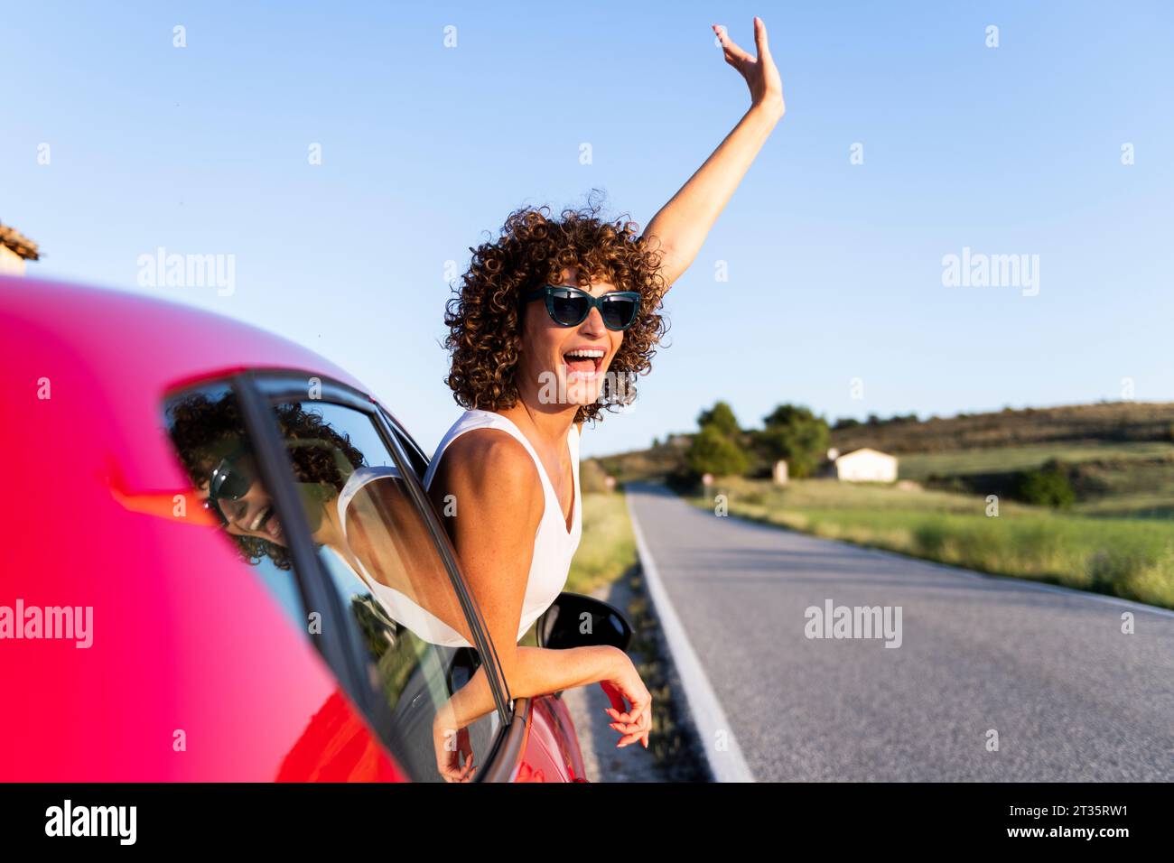 Glückliche Frau, die vom Autofenster winkt Stockfoto