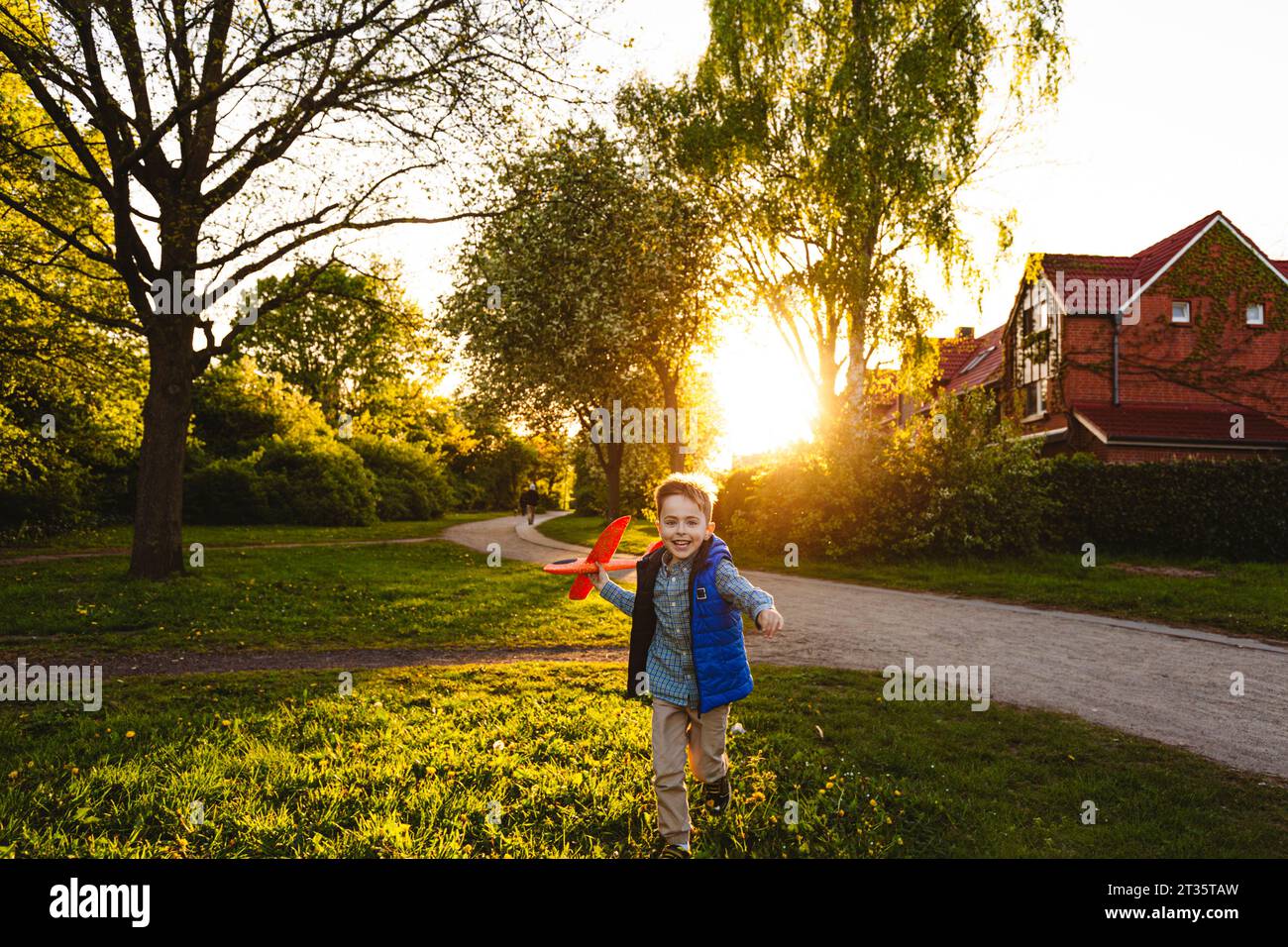 Glücklicher Junge, der bei Sonnenuntergang mit einem Spielzeugflugzeug läuft Stockfoto