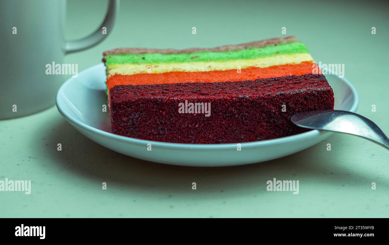 Regenbogenkuchen, lila rot gelb grün serviert auf einem Teller Stockfoto