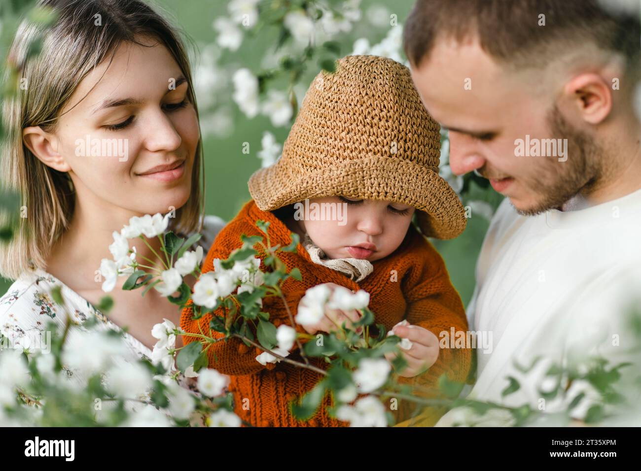 Lächelnde Eltern mit Kind, die Freizeit im Garten verbringen Stockfoto