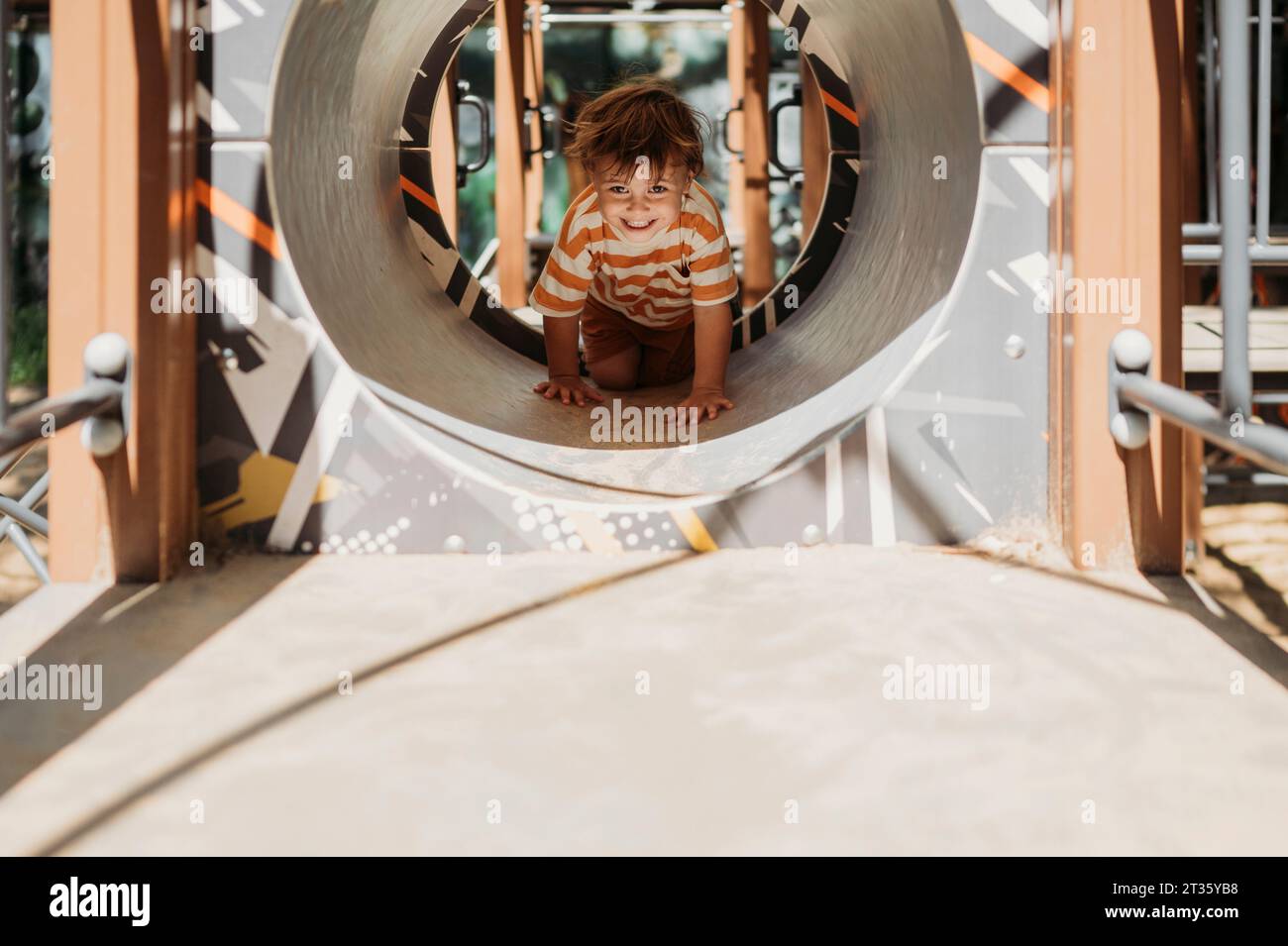 Lächelnder Junge, der in Spielgeräten kriecht Stockfoto