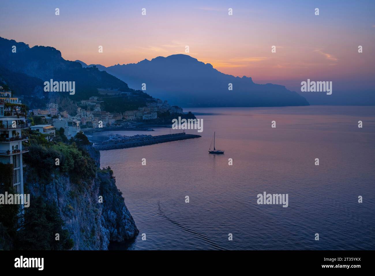 Blaues Meer mit Seeschiff in der Nähe der Stadt bei Sonnenaufgang Stockfoto
