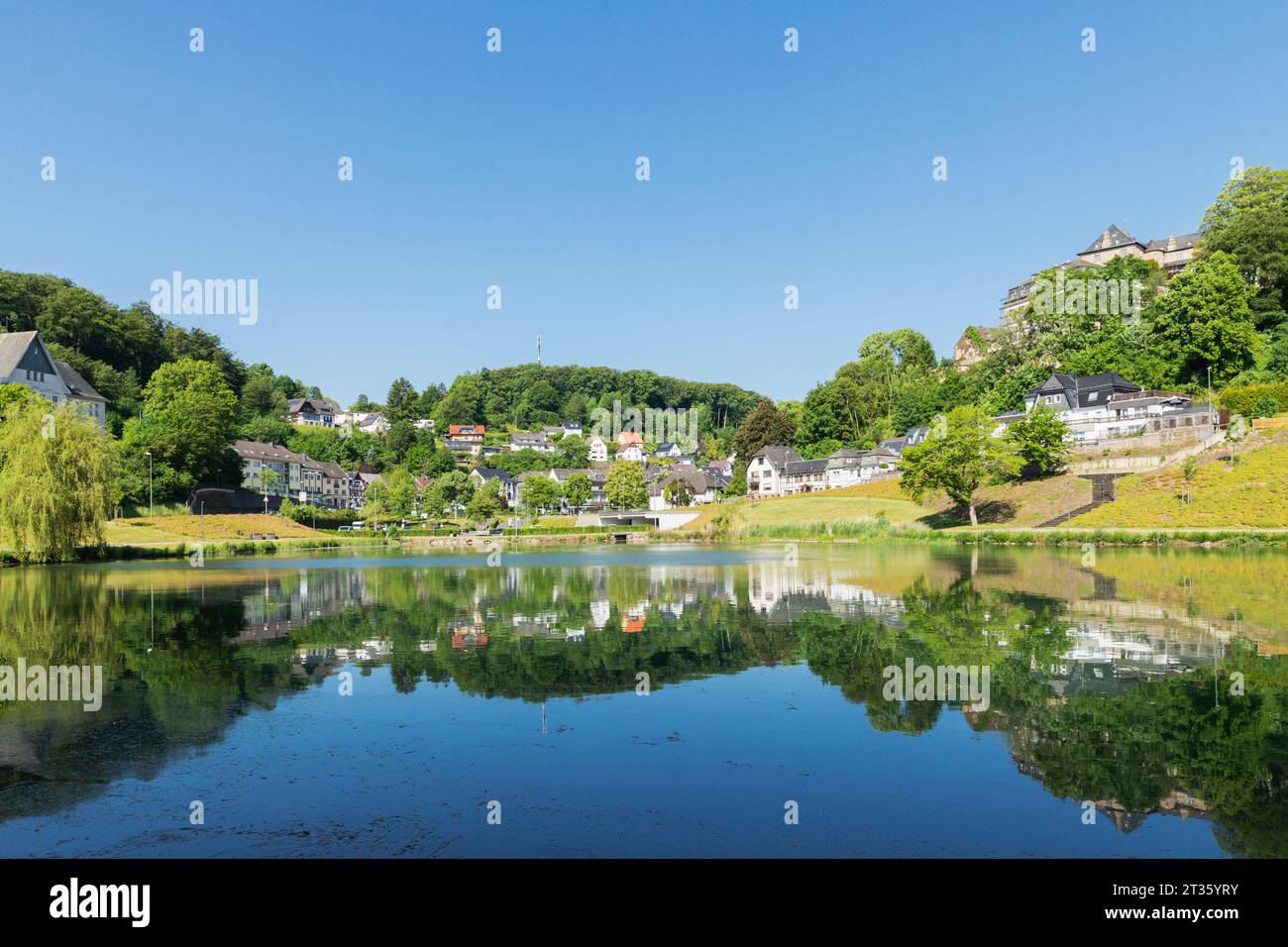 Deutschland, Nordrhein-Westfalen, Blankenheim, Schwanenweiher See mit Stadt im Hintergrund Stockfoto