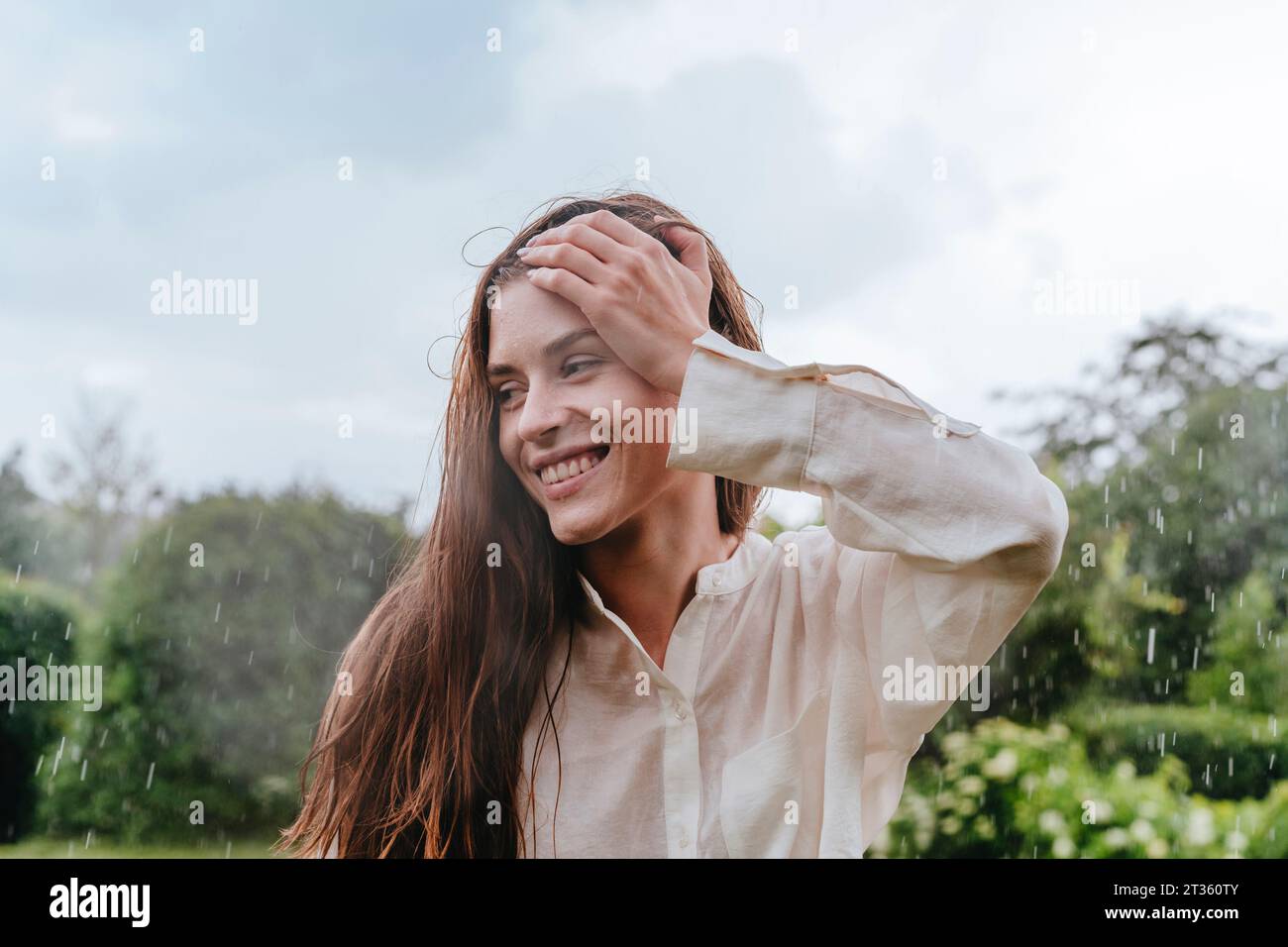 Besinnliche Frau, die im Regen im Garten steht Stockfoto