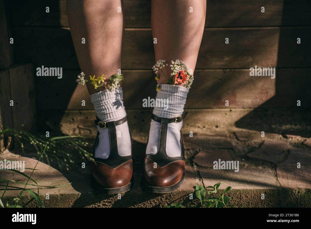 Frau mit Vintage-Schuhen mit Wildblumen in weißen Socken Stockfoto