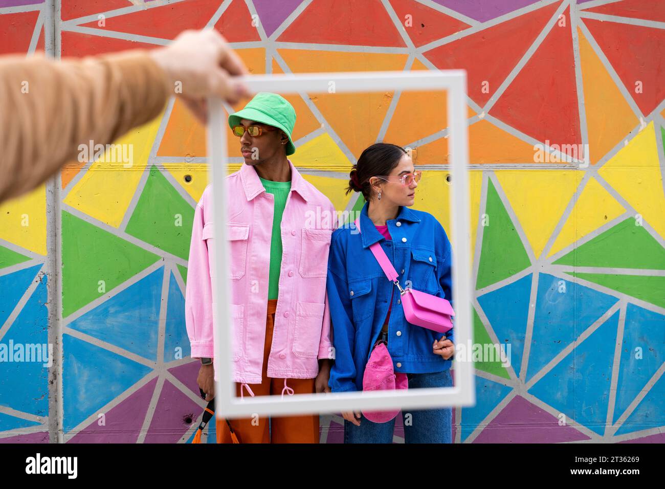 Zugeschnittener Bilderrahmen mit modischen Freunden vor farbenfroher Wand Stockfoto