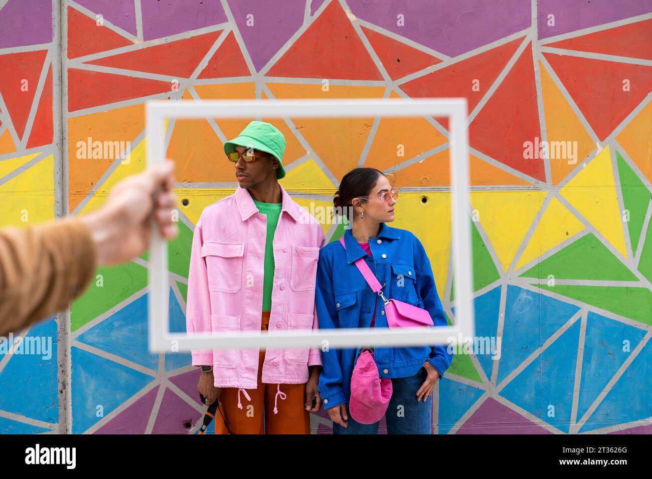 Multirassisches Paar posiert vor einer bunten Wand Stockfoto