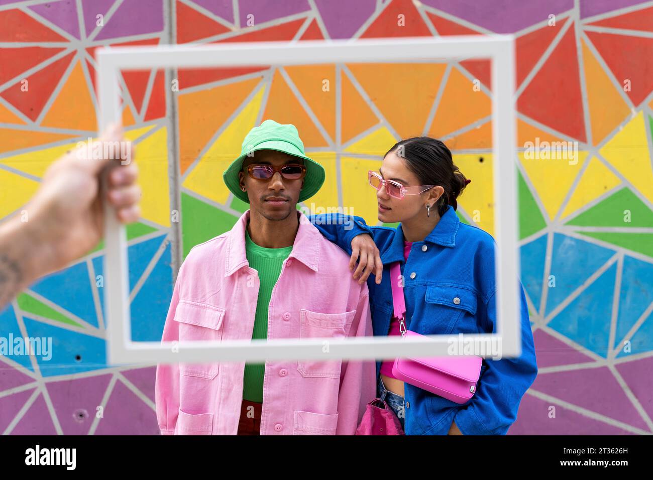 Zugeschnittener Bilderrahmen mit multirassischen Freunden vor farbenfroher Wand Stockfoto