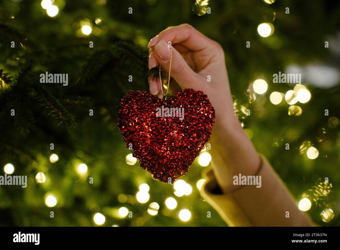 Hand einer Frau mit herzförmiger Weihnachtsdekoration Stockfoto