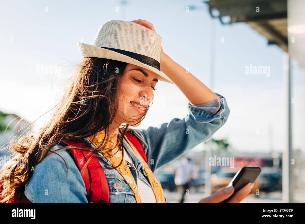 Glückliche junge Frau mit Hut mit Handy Stockfoto