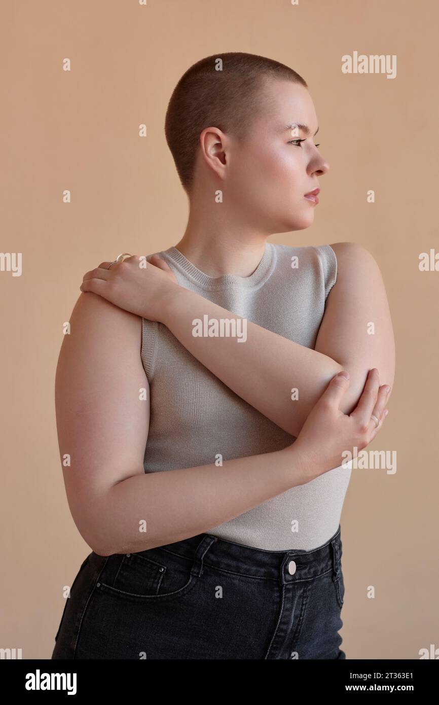 Frau mit kurzen Haaren vor beigefarbenem Hintergrund Stockfoto