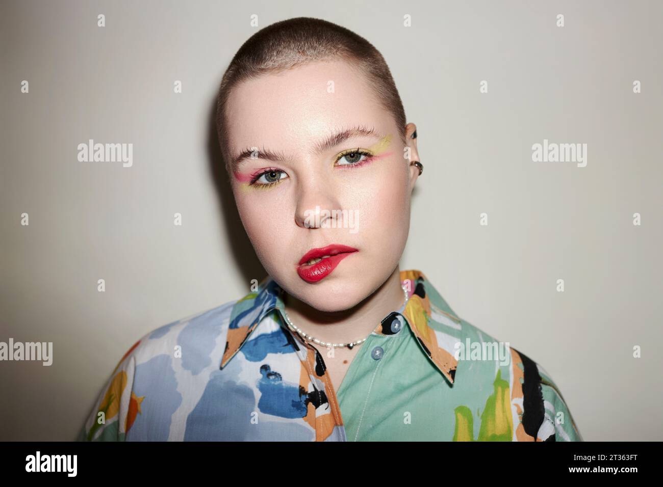 Stilvolle Frau beißt Lippen vor beigefarbenem Hintergrund Stockfoto