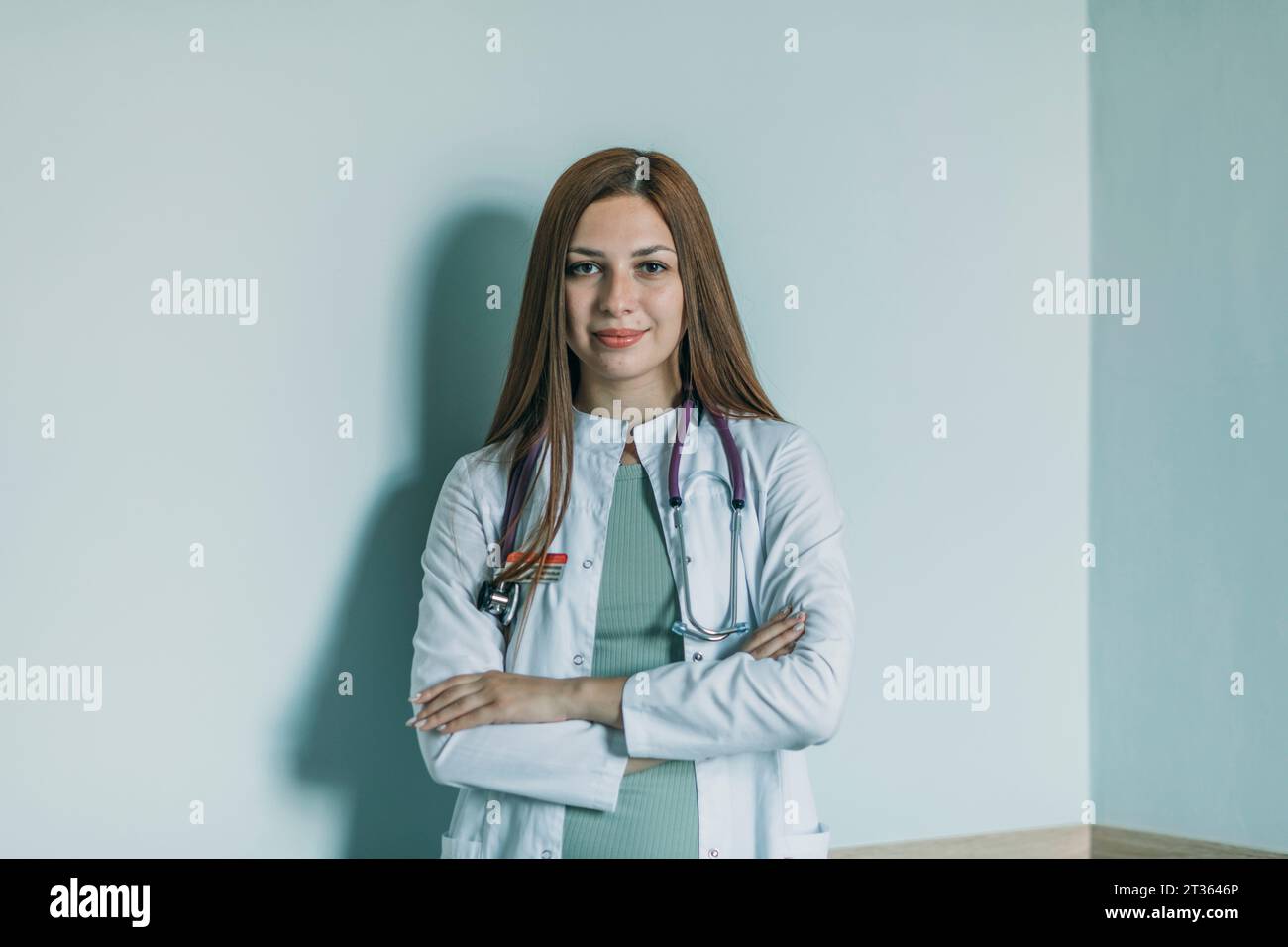 Ärztin mit überkreuzten Armen vor der Wand stehend Stockfoto