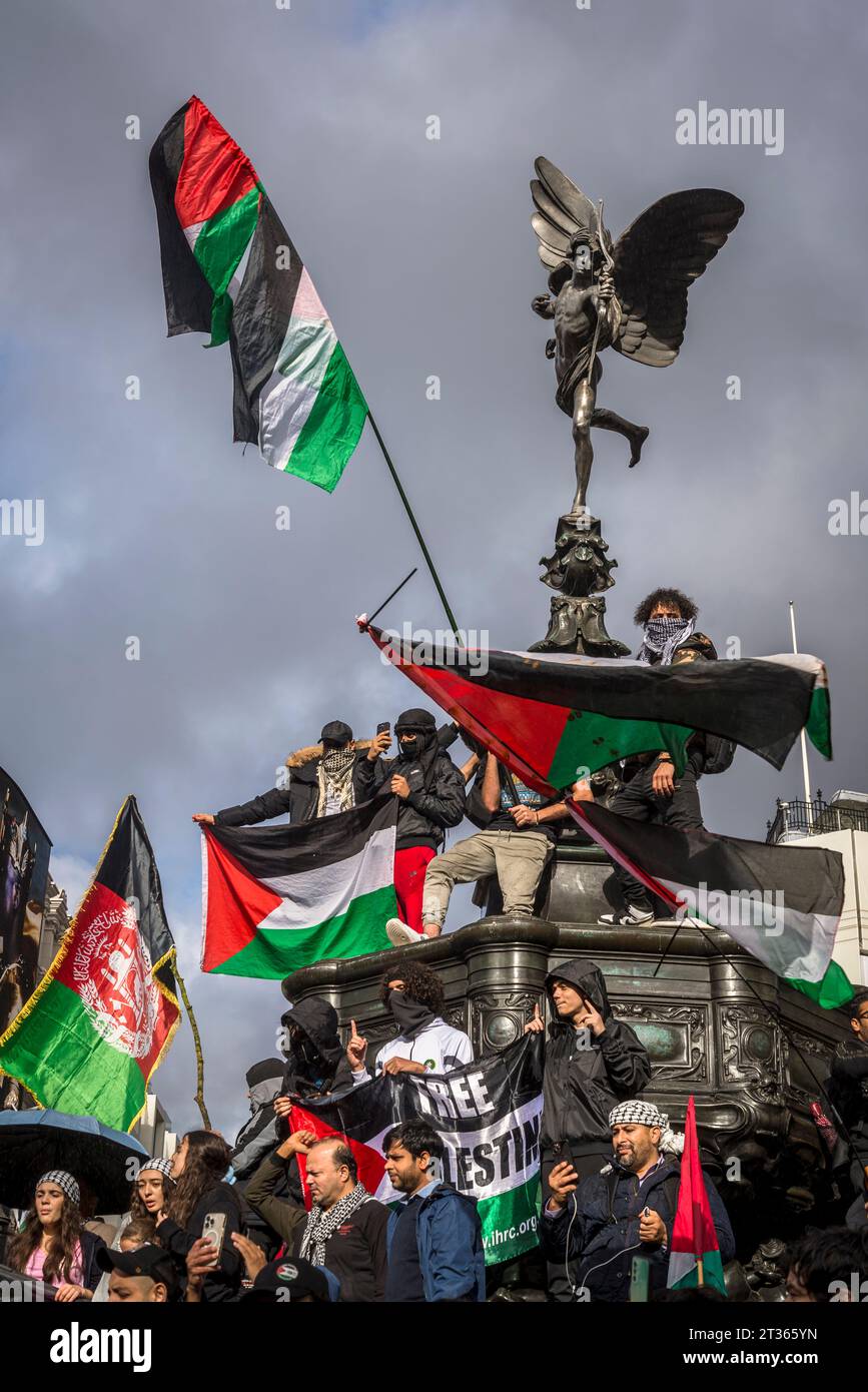 Demonstranten schwingen Fahnen auf der Eros-Statue im Piccadilly Circus, pro-palästinensische Proteste in Zentral-London am 21.10.2023, England, Großbritannien Stockfoto