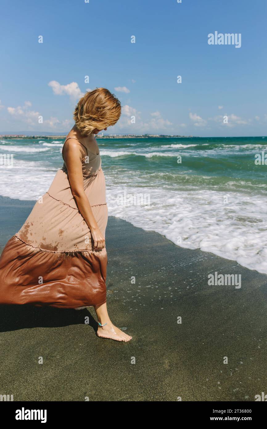 Frau, die auf nassem Sand in der Nähe des Strandes steht Stockfoto