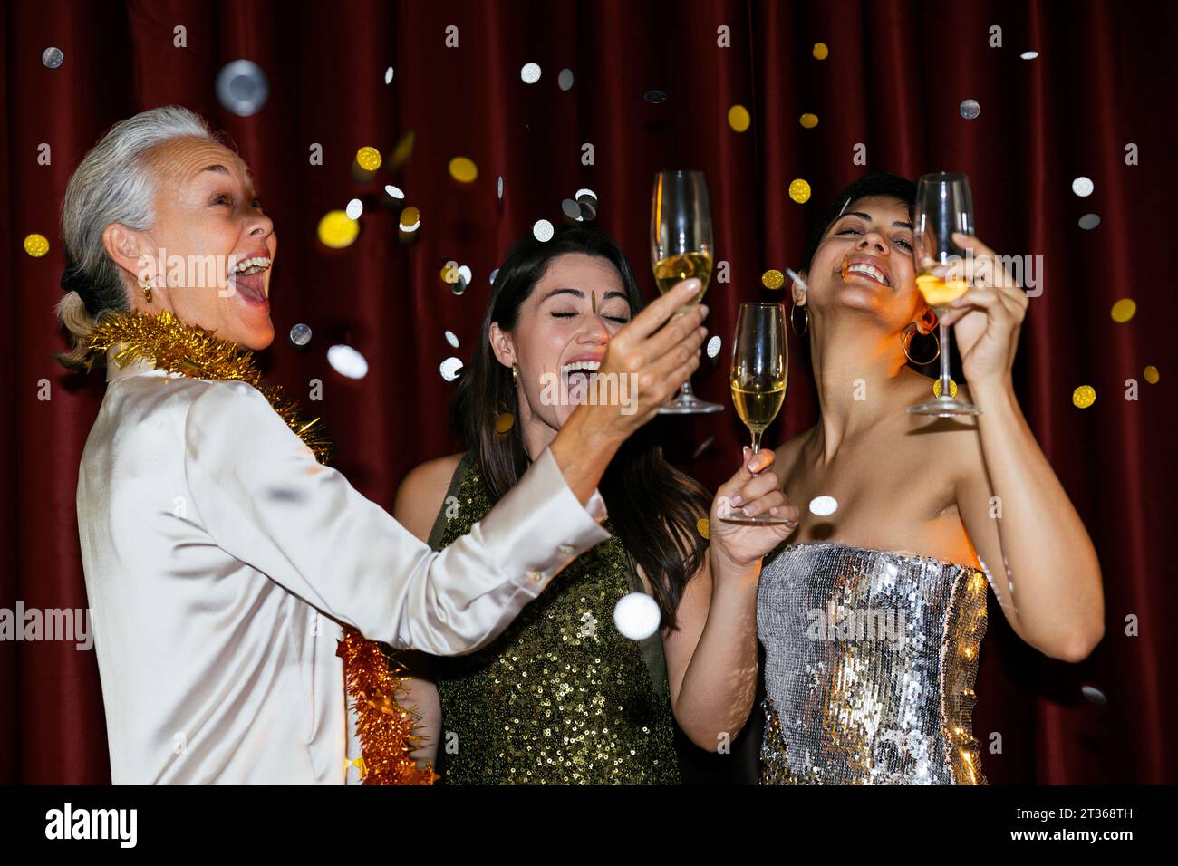 Glückliche Frauen mit Sektgläsern tanzen bei der Neujahrsfeier Stockfoto